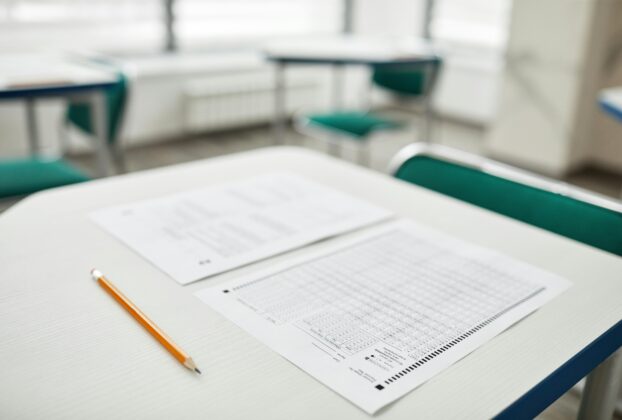 Close-up of exam papers and a pencil on a classroom desk, ready for a test.